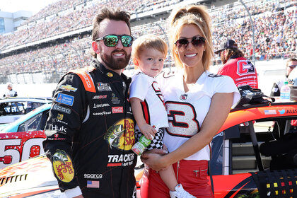 Austin Dillon with his wife and child, posing at a nascar event