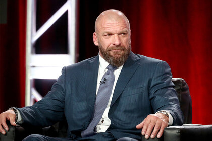 Triple H sitting in a chair, wearing a suit