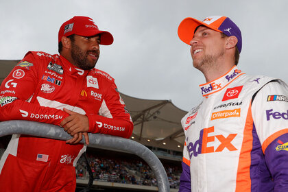 Bubba Wallace and Denny Hamlin smiling while speaking to one another