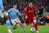 Andrew Robertson of Liverpool and Phil Foden of Manchester City chase the ball during a game.