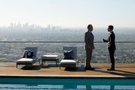 Greg Litvak and Ted Black talk in front of the LA city scape by a pool on Suits L.A Season 1 Episode 1