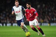 Bruno Fernandes of Manchester United and Dejan Kulusevski of Tottenham Hotspur chase after the ball during a game.