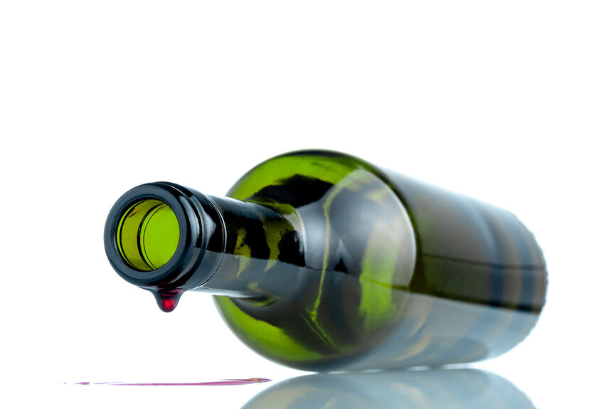 A wine bottle laying down with the last drop falling