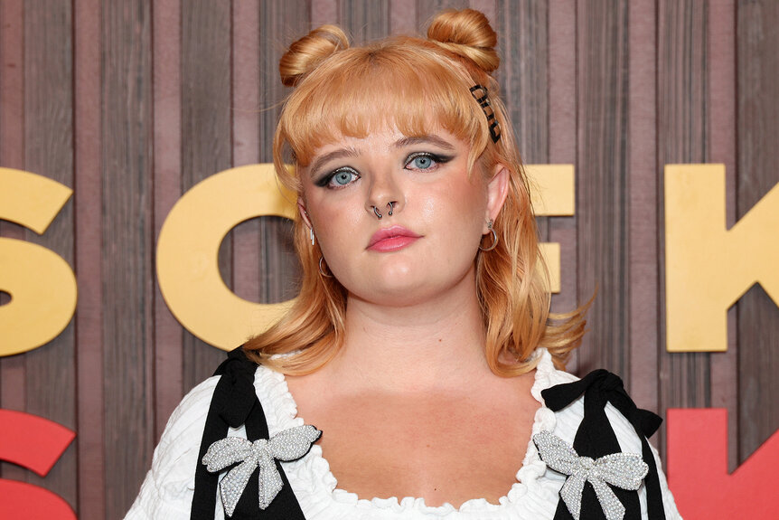 Milly Shapiro wears space buns and red lipstick on the red carpet for Kinds of Kindness