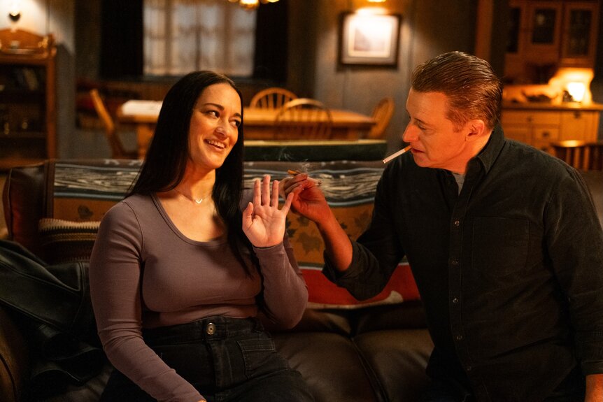 Harry Vanderspeigle (Alan Tudyk) offers Asta Twelvetrees (Sara Tomko) a cigarette on Resident Alien Episode 401.