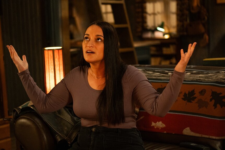 Asta Twelvetrees (Sara Tomko) raises her arms on Resident Alien Episode 401.