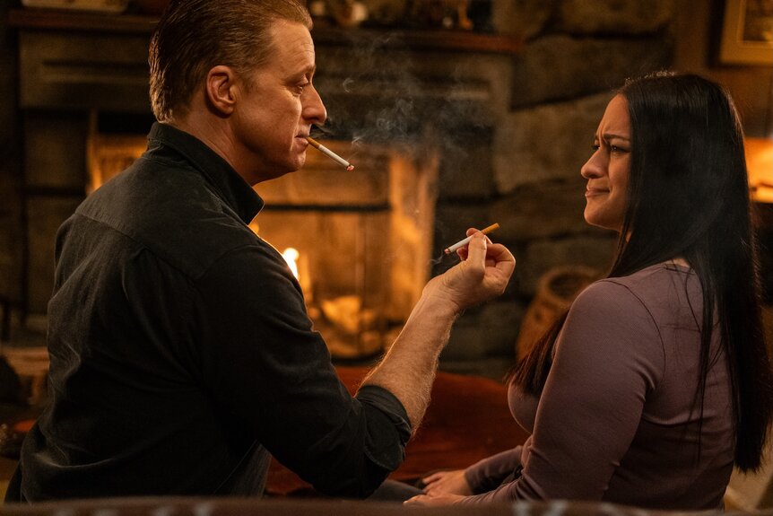 Harry Vanderspeigle (Alan Tudyk) offers Asta Twelvetrees (Sara Tomko) a cigarette on Resident Alien Episode 401.