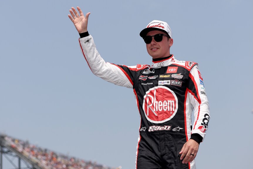 Christopher Bell waves in his NASCAR suit.
