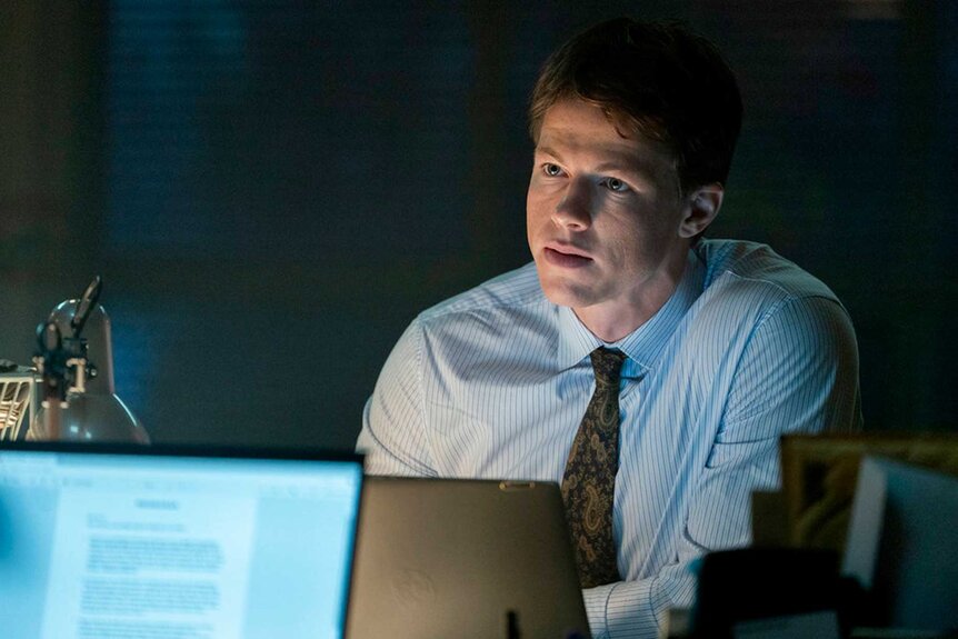 The Rainmaker star Milo Callaghan as Rudy Baylor sitting at computer